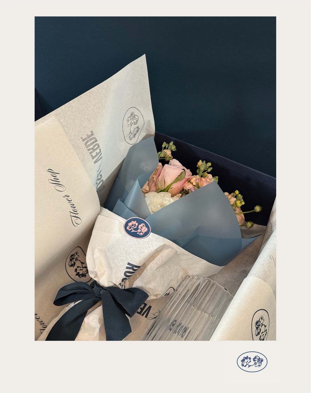 Flower Box abierta con bouquet envuelto en papel Rosa y Verde, listón azul y florero de vidrio