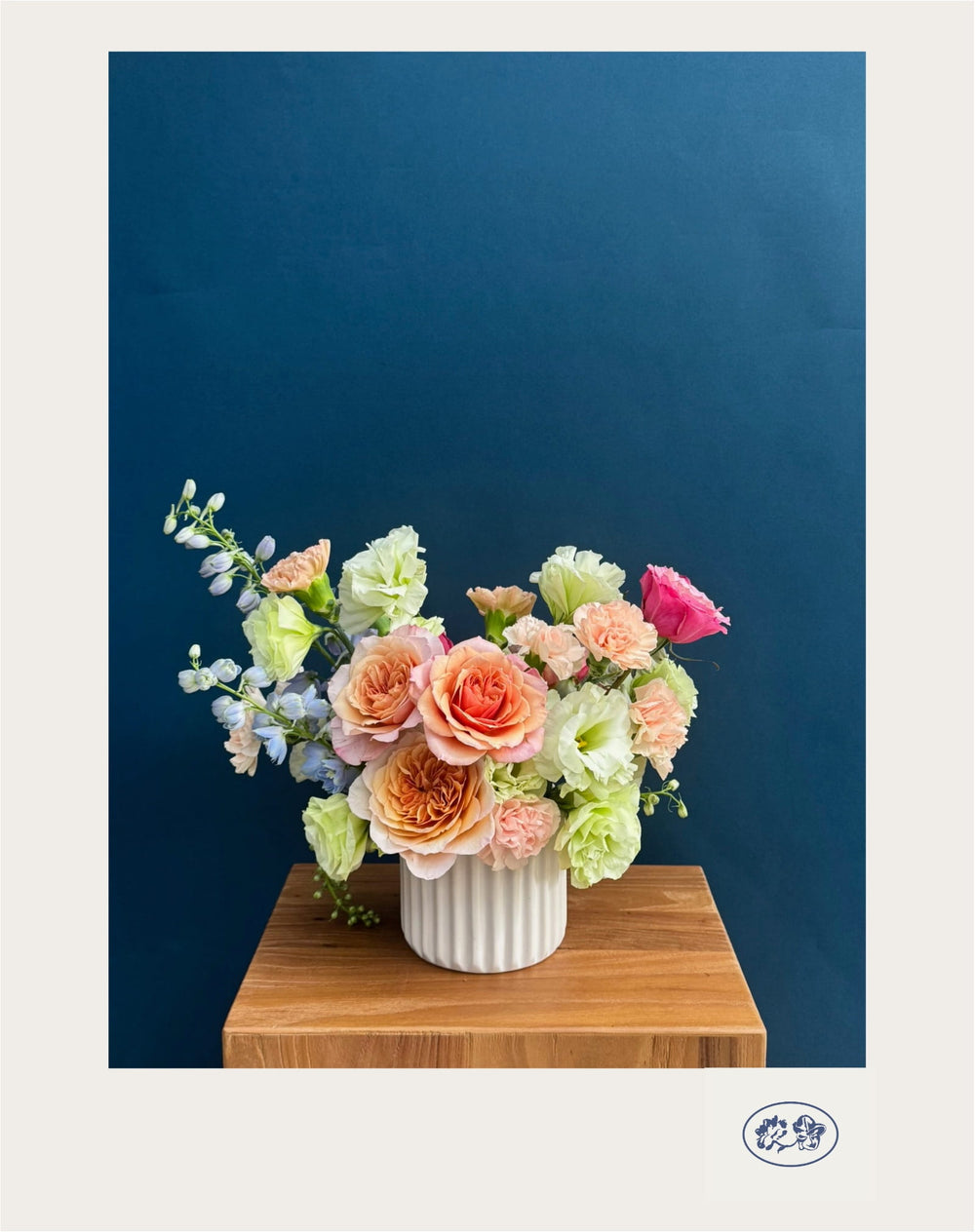 Arreglo floral MariTere en tonos naranjas, azules y verdes con claveles, delphinium, lisianthus y rosas